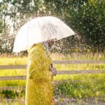 A man in a yellow raincoat in the rain. It's raining and the sun is shining
