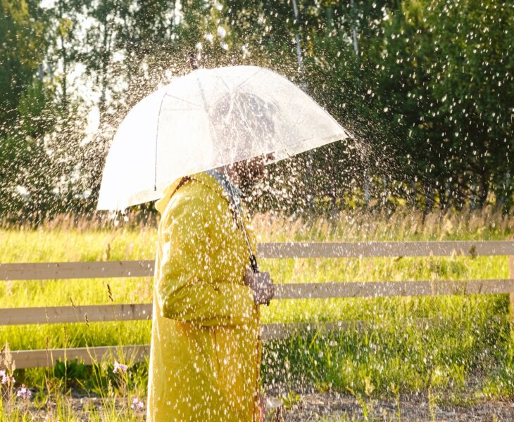 A man in a yellow raincoat in the rain. It's raining and the sun is shining