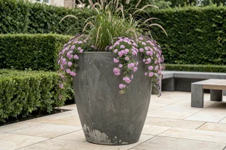 Grand pot de fleur extérieur de 100 cm en béton anthracite mat sur terrasse contemporaine avec graminées et verbena